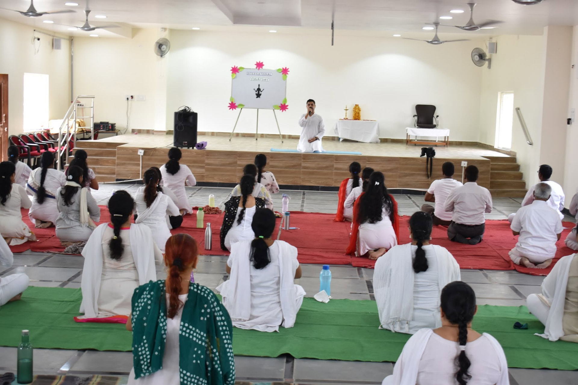 Rohit leading a group yoga session in a bright studio hall